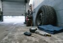 Auto a motorka v provozu: kontroly, zima a nákup ojetiny Klíče od auta a měřič tlaku na dílenském stole vedle zimní pneumatiky