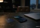 Jak poznat finanční podvod dřív, než zaplatíte Telefon na stole vedle platební karty a zavřeného notebooku ve večerním světle
